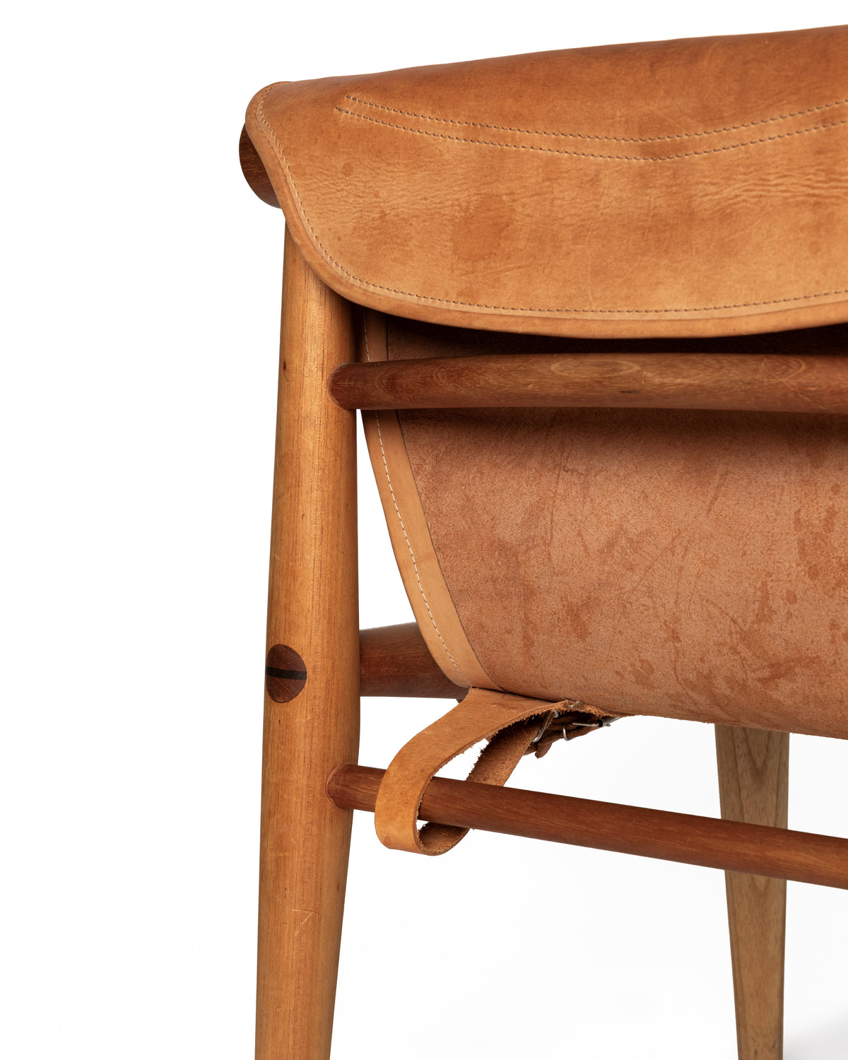 mid-century modern wooden chair featuring a warm tan leather seat and a matching leather side strap, set against a solid white background.