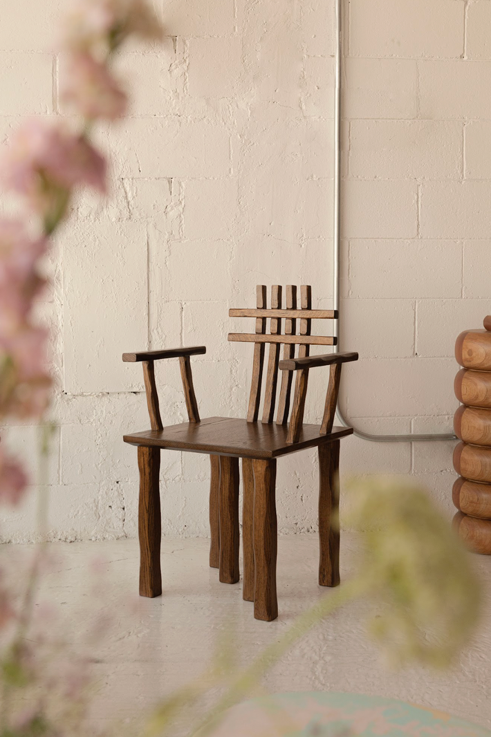 Two wooden chairs against a textured white wall with floral elements.