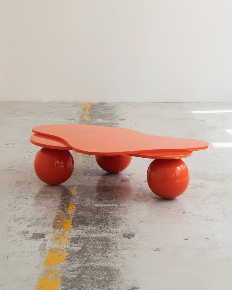 Orange table with spherical bases on a concrete floor