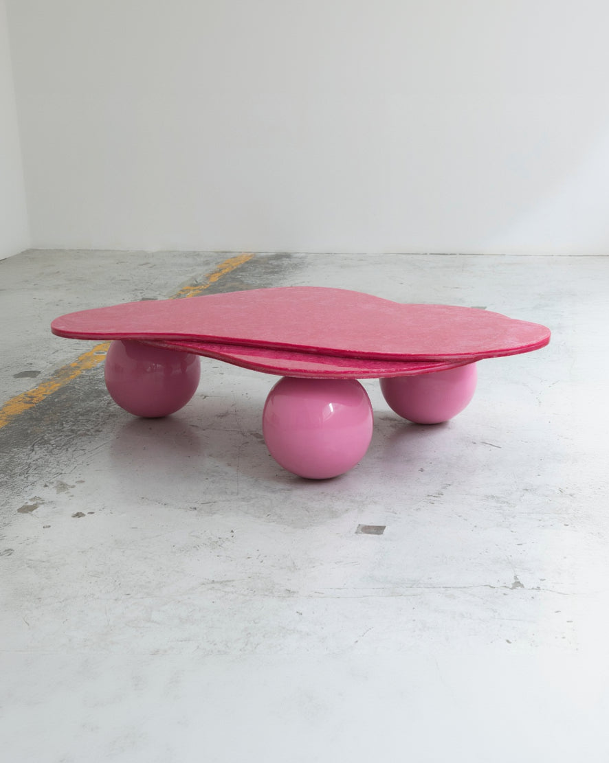 Pink table with spherical bases on a concrete floor