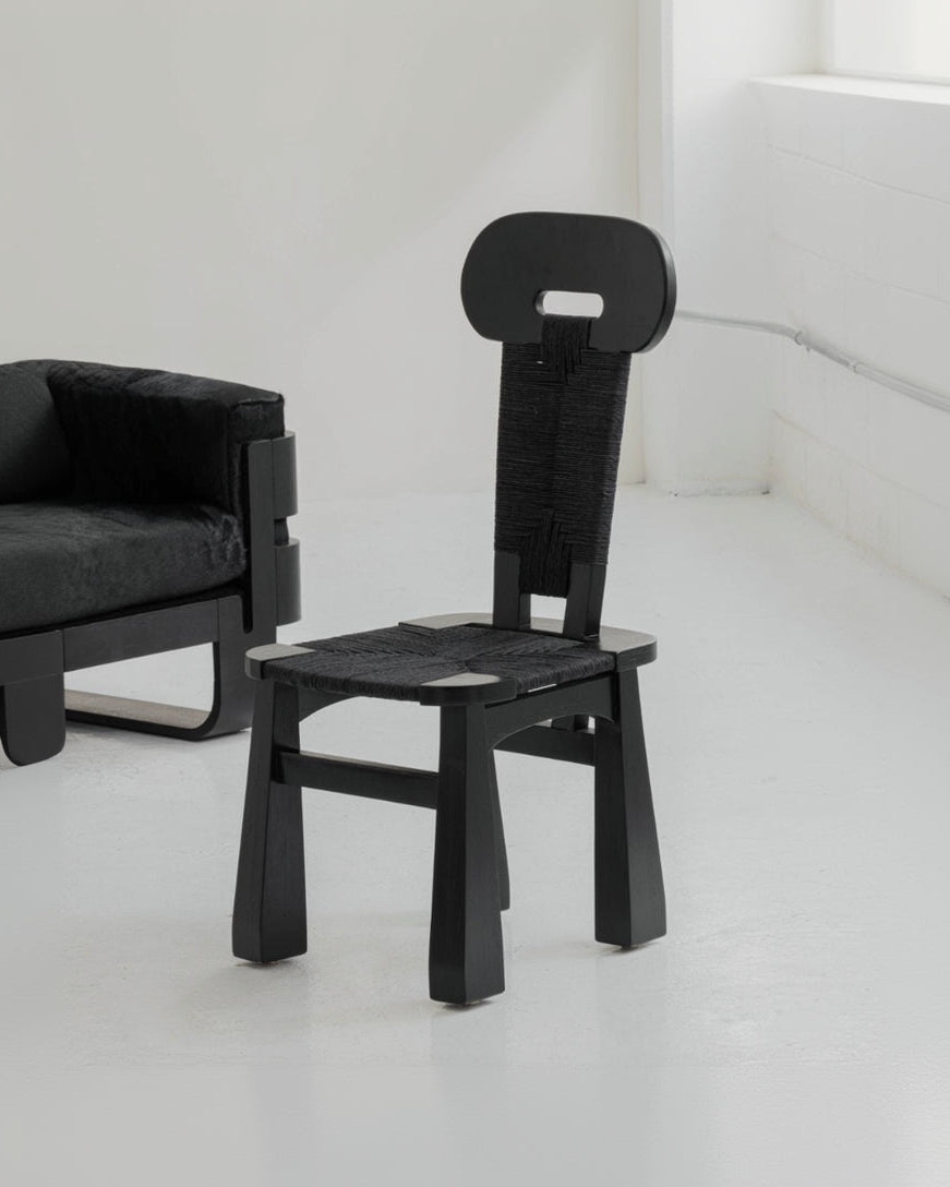 Black chair in a minimalistic room with white floor and light gray walls.
